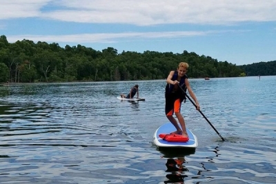 Boy paddle boards on lake